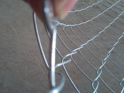 PVC coated chain link fence with diamond shape holes and twist ends is placed on the floor.